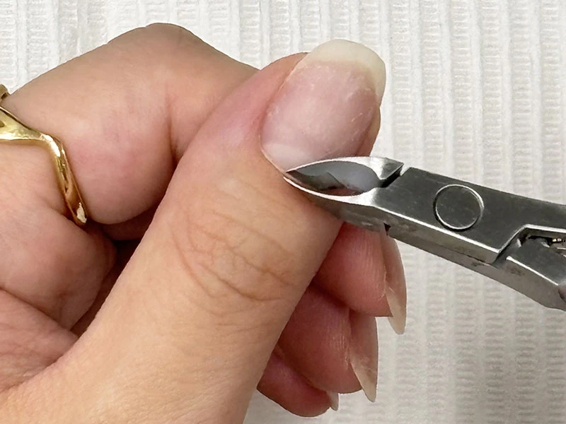 セルフネイルのやり方の工程で余分な甘皮をニッパーでカットしている様子