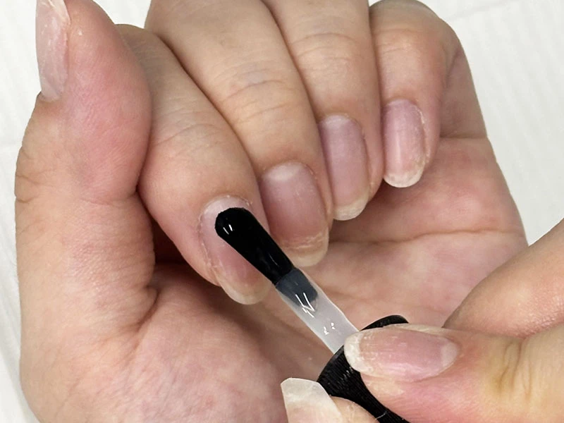 セルフネイルのやり方の工程で甘皮側からベースコートを塗り始めている様子